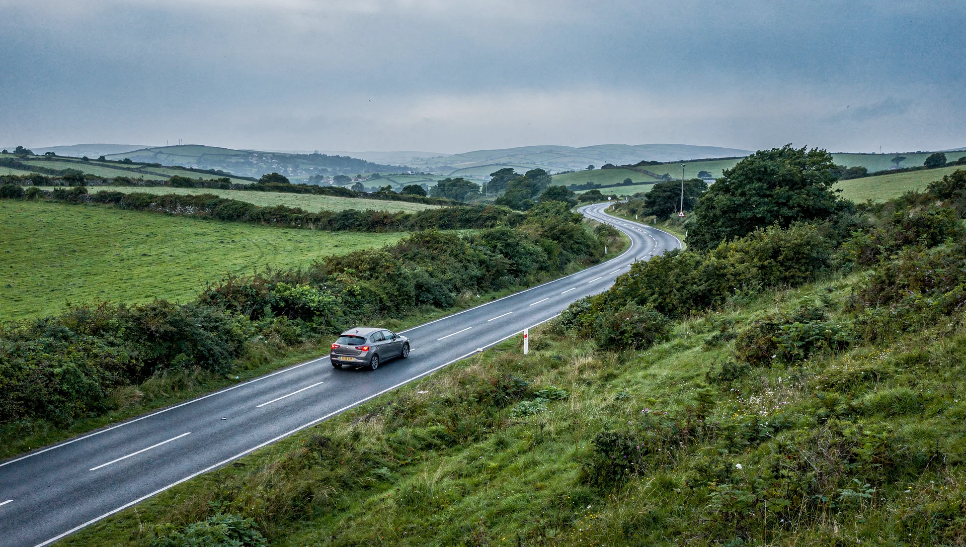 A car on a winding road through Ireland’s green hills